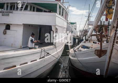 Un uomo che pulisce le mani dopo la verniciatura barca a Paotere Porto di Makassar, Indonesia. Foto Stock