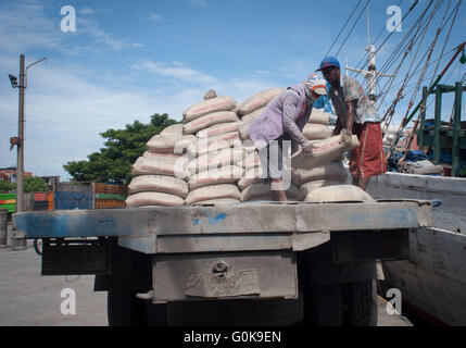 Lavoratori caricati sacchi di cemento per lo scafo di una imbarcazione a Paotere Porto di Makassar, Indonesia. Foto Stock