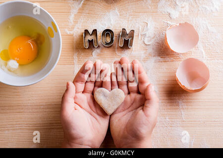 La festa della mamma. Cuore cookie, cottura, cookie cutter. Backgr in legno Foto Stock