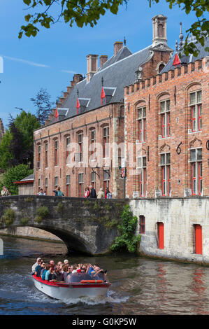 Barca piena di turisti di passare sotto il ponte Blinde-Ezel in Huidenvettersplein, Bruges, Belgio. Foto Stock