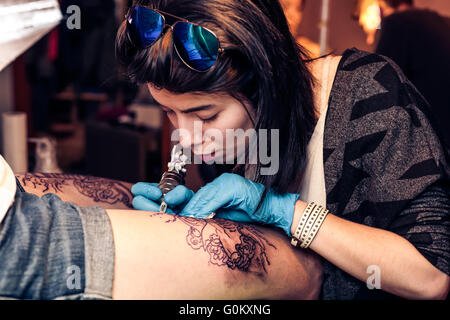 Donna tattooer che mostra il procedimento di preparazione di un tatuaggio Foto Stock