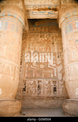 Dipinti egiziani, carving figure e geroglifici in colonne e una parete di pietra miliare tempio di Ramses o Ramesse III a Medinet Foto Stock