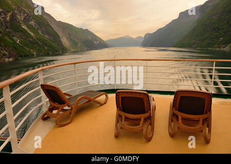 Svuotare lettini per prendere il sole sul ponte posteriore di una nave da crociera vela lungo un fiordo norvegese poco dopo l'alba. Foto Stock