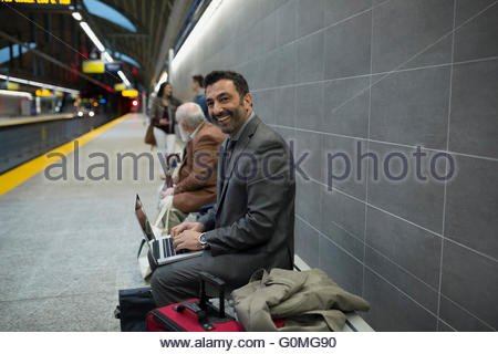 Ritratto sorridente imprenditore banco portatile stazione della metropolitana platform