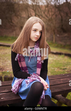 Ragazza adolescente guardando in lontananza mentre seduto su un tavolo da picnic Foto Stock