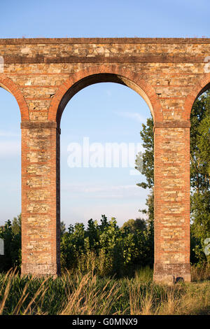 Sezione di arco dell'Acquedotto Nottolini in Toscana vicino a Lucca, Italia. Serata calda luce. Classici toscani texture e toni. Foto Stock