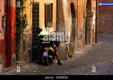 Postino sulla bici del motore consegna la posta, Tuscania, provincia di Viterbo, Lazio, Italia Foto Stock