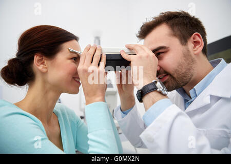 Ottico con pupilometer e paziente alla clinica oculistica Foto Stock