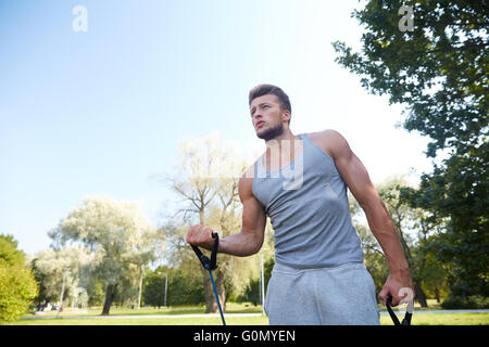 Giovane uomo esercitando con espansore in estate park Foto Stock