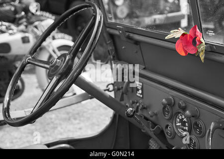 Veicolo in jeep vintage della seconda guerra mondiale con papavero rosso ricordo sul cruscotto Foto Stock