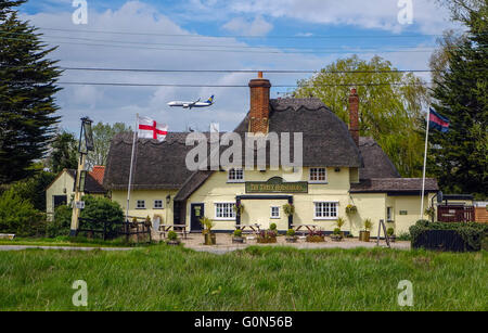 Tre pattini del cavallo pub con il tetto di paglia, vicino l'aeroporto di Stansted, Essex, con l'inglese St George bandiera Foto Stock