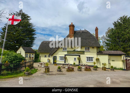 Tre pattini del cavallo pub con il tetto di paglia, vicino l'aeroporto di Stansted, Essex, con l'inglese St George bandiera Foto Stock