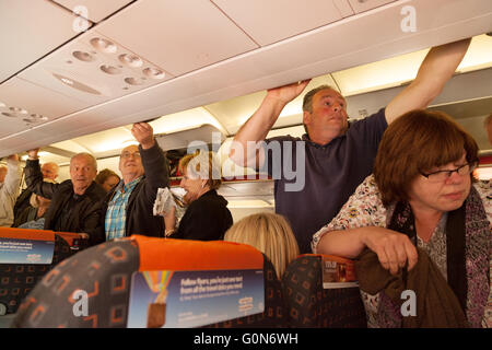 I passeggeri del trasporto aereo arrivare i loro bagagli a mano da armadietti sopraelevati su un volo Easyjet da Southend aeroporto a Malaga Spagna Foto Stock