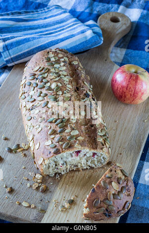 Mirtillo rosso, i semi di zucca e Orange focaccia sulla breadboard di legno. Foto Stock