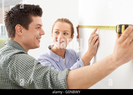 Coppia giovane la misura parete nella nuova casa Foto Stock