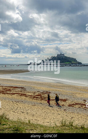 Marazion spiaggia fotografato nel sole con tre colleghe di camminare sulla spiaggia e St Michael's Mount in background Foto Stock