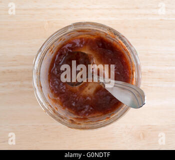 Vista superiore di quasi un vaso vuoto di fragole conserve con un cucchiaio su una tavola di legno alto. Foto Stock