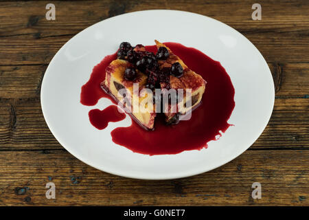 Il budino con le prugne secche, le uve secche di Corinto sulla parte superiore di una piastra bianca su una tavola di legno Foto Stock