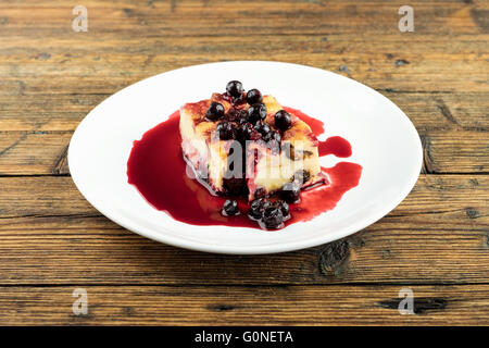 Il budino con le prugne secche, le uve secche di Corinto sulla parte superiore di una piastra bianca su una tavola di legno Foto Stock