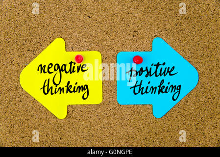 Messaggio pensiero negativo contro il pensiero positivo sul giallo e blu note di carta come frecce opposte imperniata sulla bacheca di sughero con thumbtacks. Scelta immagine concettuale Foto Stock