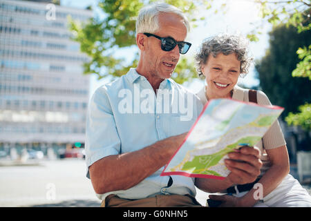 Coppia senior guardando la mappa della città. Uomo maturo e la donna seduti all'aperto in città la lettura di una mappa per la direzione. Foto Stock