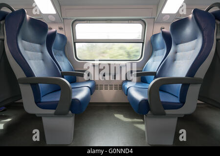 Quattro vuoto azzurro sedi affacciate in moderno treno europeo. Ferrovia di viaggio o il concetto di trasporto Foto Stock