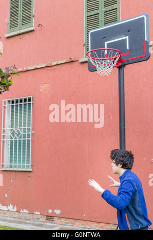 La formazione del ragazzo le posizioni difensive in una partita di basket grunge parco giochi vicino alla parete di pelatura di una vecchia casa Foto Stock