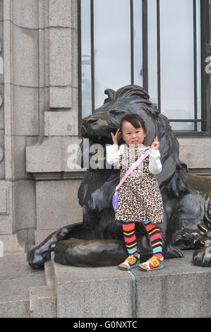 Giovane ragazza prima di Lion statua al di fuori dell'edificio HKSB, Bund, Shanghai, Cina. Foto Stock