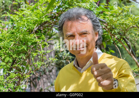Uomo di mezza età sotto il Maggiociondolo in giardino verde Foto Stock