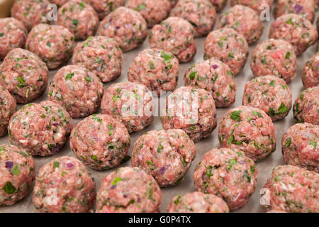 Righe di materie in casa polpette di carne preparati per la cottura su un vassoio Foto Stock