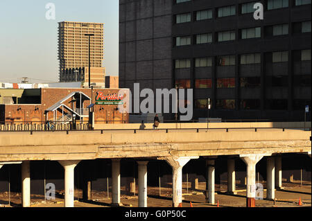 Chicago, Illinois, Stati Uniti d'America. Un uomo solitario fa il suo modo lungo una strada solitaria in Chicago supportato da concreti e colonne chiaramente bisogno di riparazione. Foto Stock