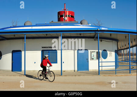 Un ciclista solitario passando per il punto di riferimento a barchetta boathouse a Chicago North Avenue Beach. Chicago, Illinois, Stati Uniti d'America. Foto Stock