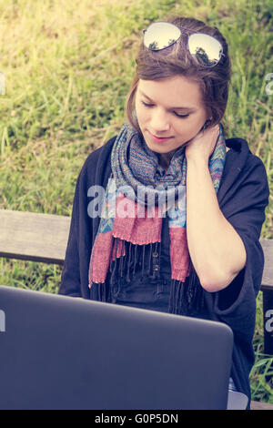 Giovane donna strofinando il collo mentre si lavora su un computer portatile. Foto Stock