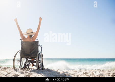 Sedia a rotelle donna seduta con le braccia in alto Foto Stock