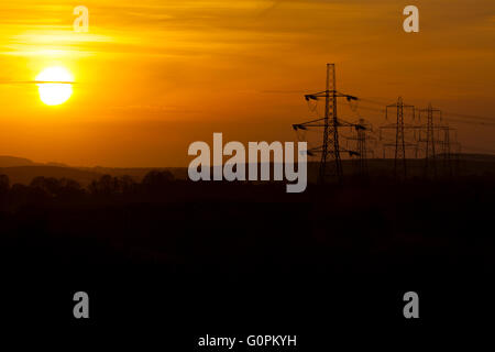 Il tramonto di stagliano electricy tralicci sulla montagna Halkyn, Wales, Regno Unito Foto Stock