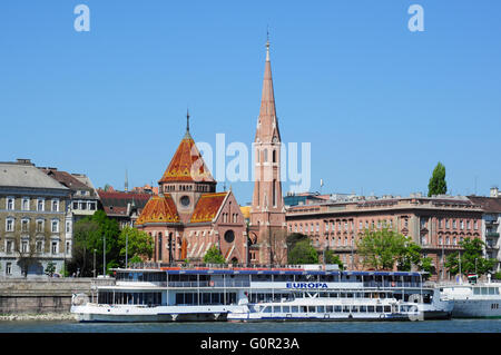 Il Fiume Danubio nave da crociera e Buda chiesa calvinista, Budapest, Ungheria Foto Stock