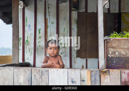 Piccolo Ragazzo di Papua con la faccia triste di un portico di casa sua Foto Stock