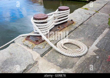 Posto barca Bitt bitte o gancio su un molo di pietra bordo avvolto ordinatamente la cima di ormeggio attaccata Foto Stock