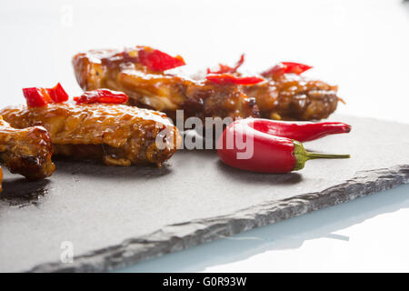 Alette di pollo fritte su un nero ardesia piastra Foto Stock