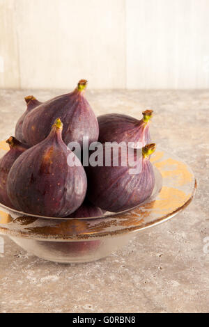 Tutto fichi freschi in una ciotola di vetro su una superficie delle mattonelle di ceramica. Foto Stock