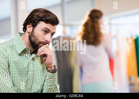 Annoiato uomo in attesa di sua moglie mentre la donna dal portabiti Foto Stock