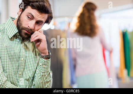 Annoiato uomo in attesa di sua moglie mentre la donna dal portabiti Foto Stock