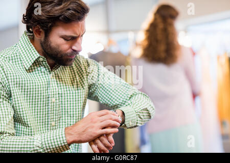 Annoiato uomo in attesa di sua moglie mentre la donna dal portabiti Foto Stock