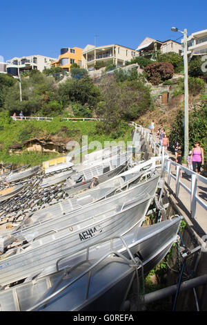 La gente camminare lungo la passeggiata costiera con una fila di gommoni di alluminio a Gordons Bay, Sydney. Foto Stock