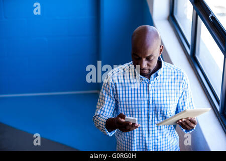 Vista anteriore del business man standing mentre usando tavoletta digitale Foto Stock
