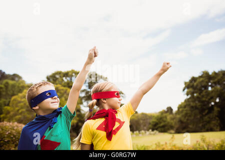 Due graziosi bambini fingendo di volare in costume da supereroe Foto Stock