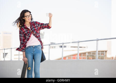 Hipster con lo skateboard a scattare foto Foto Stock