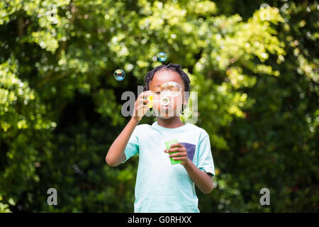 Un ragazzino soffiare bolle Foto Stock