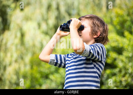 Ritratto di ragazzo simpatico cercando qualcosa con il binocolo Foto Stock