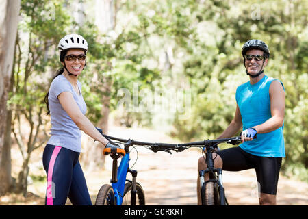 Coppia sorridente e in posa con le loro biciclette Foto Stock